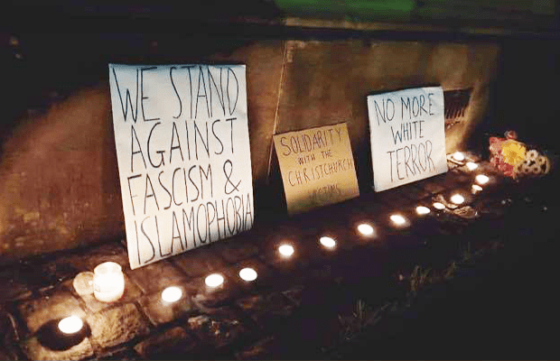 An image of the vigil on Monday night, with candles and placards reading “we stand against fascism Islamophobia,” “Solidarity with the Christchurch victims” and “No more white terror,” surrounded by a series of candles."