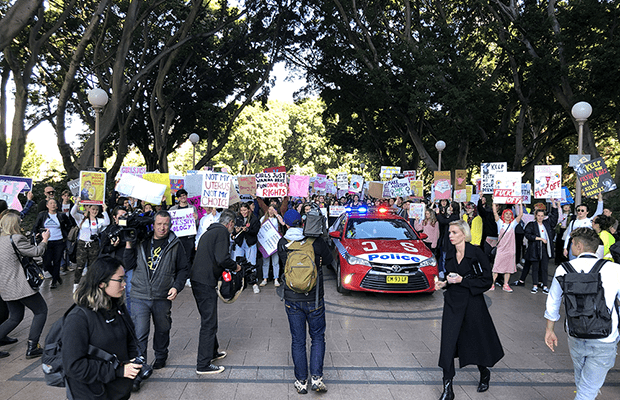 Photograph: the front of the march walking through Hyde Park, people holding pro-choice posters, and among the crowd is a police car. In front of the crowd are other journalists photographing the march.