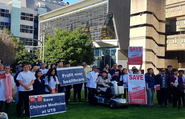 students and staff on UTS alumni green hold placards which read healthcare over profit