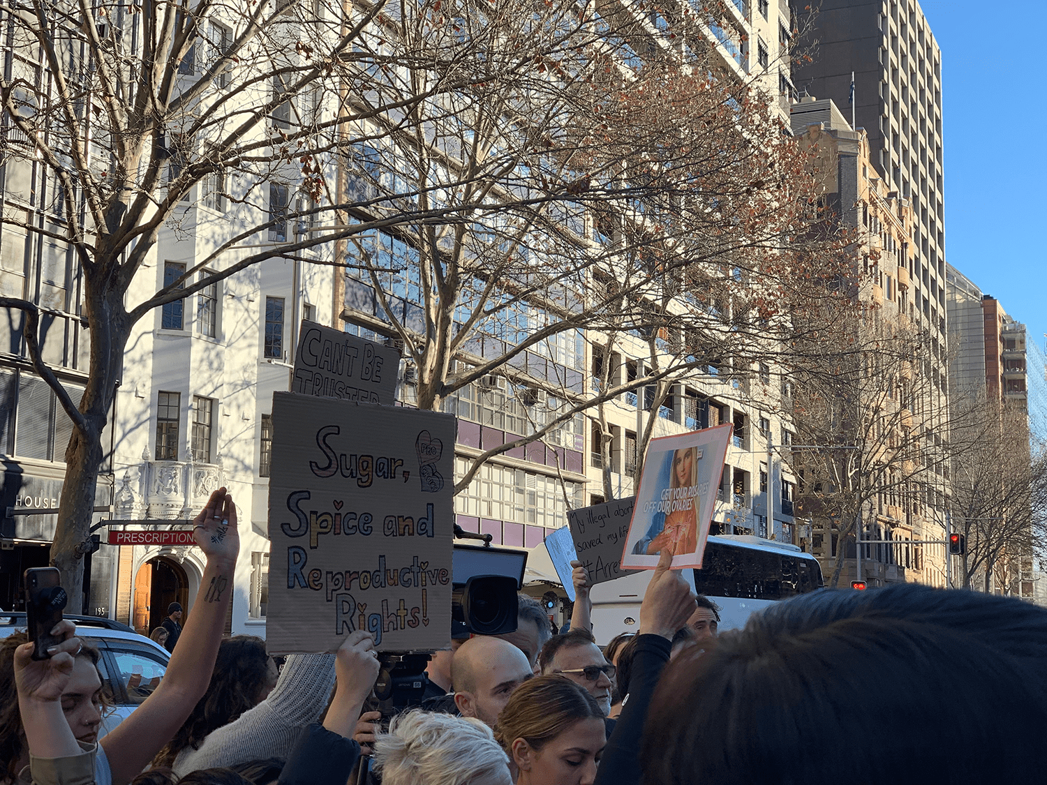 Photo of the pro life and pro choice protesters next to each other. A pro choice protester holds a sign that reads, "Sugar, spice and reproductive rights."