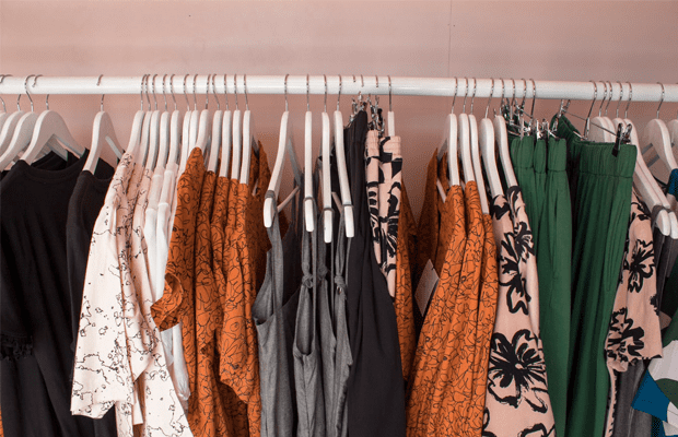 A photo of a coatrack filled with a random assortment of clothing on coathangers.