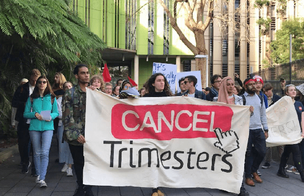 A photo of students marching at UNSW holding a banner that reads "cancel trimesters".