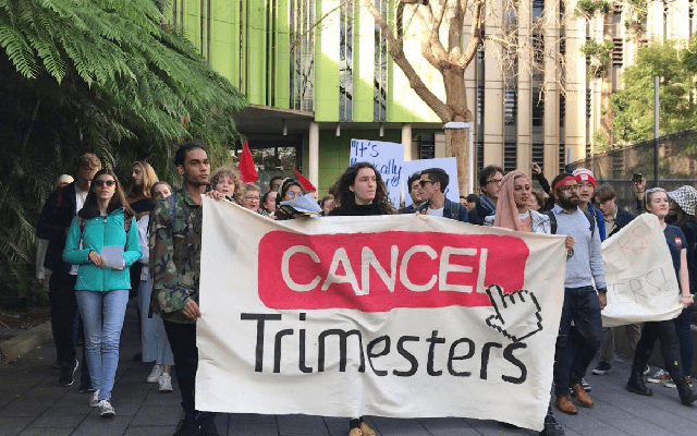 A photo of students marching at UNSW holding a banner that reads "cancel trimesters".